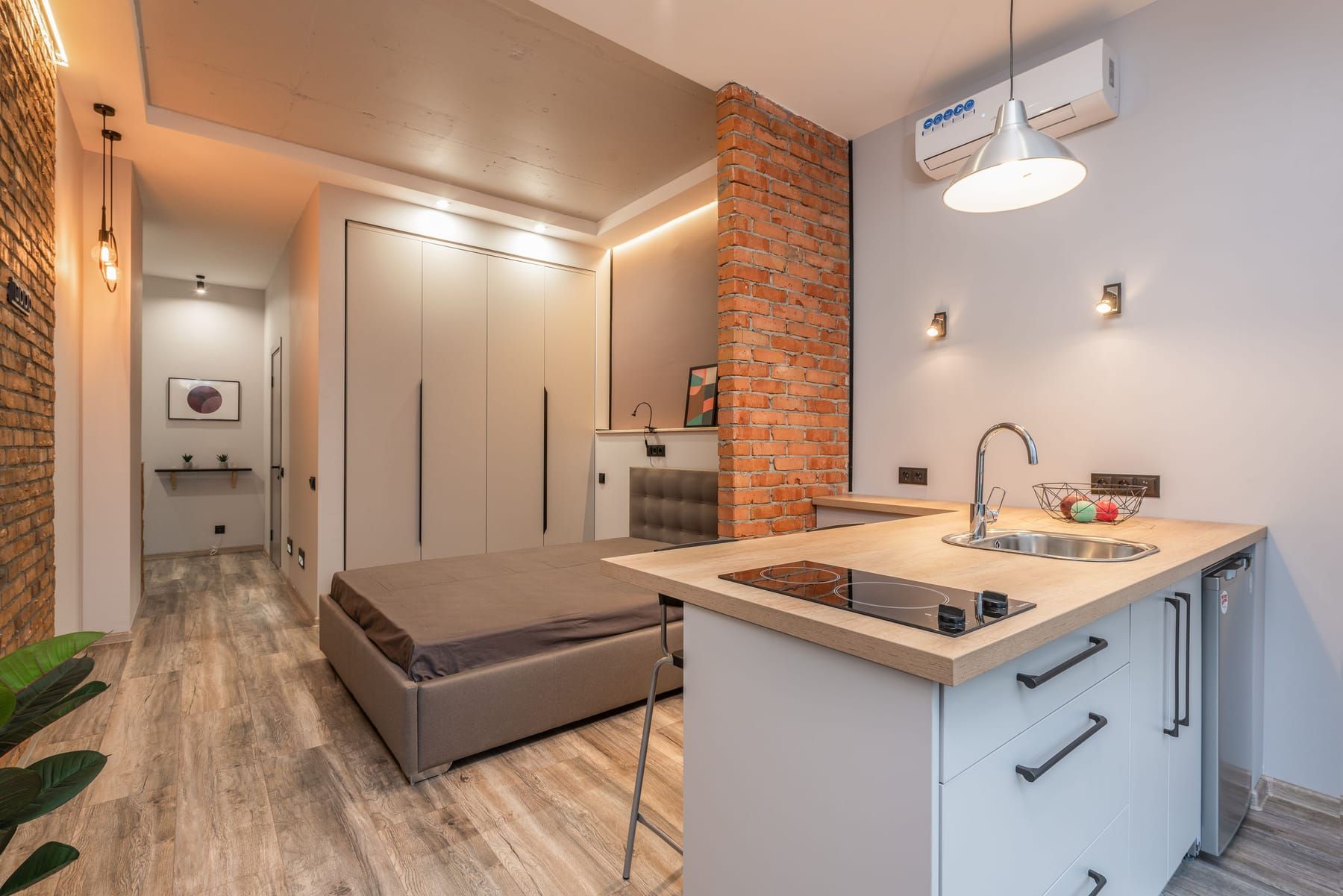 Elements included in a SpazioLiv studio apartment interior: living area, compact kitchen and wardrobe